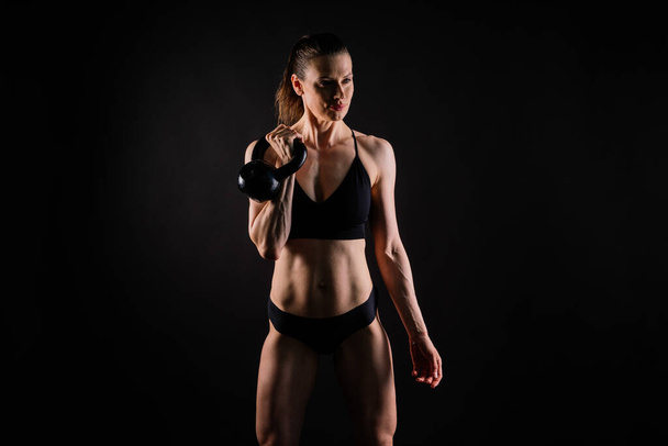 Sport, aktív életmód koncepció. Mosolygó erős és karcsú fitness női sportoló kezében vízforraló harangok - Fotó, kép