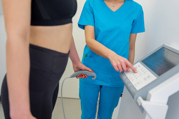 Un operatore sanitario assiste una donna con un test di composizione corporea utilizzando attrezzature avanzate. - Foto, immagini
