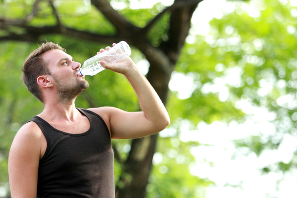 male runner drinking mineral water at the break after running - Photo, image