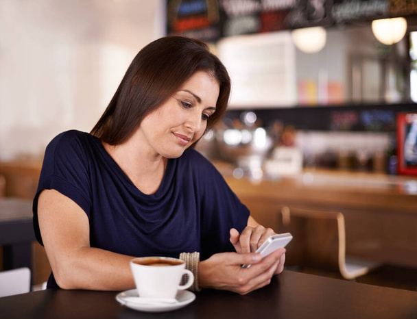 Mujer, lectura y teléfono en las redes sociales en la cafetería y el cliente relajarse con café con leche en el restaurante. Feliz, persona y el teléfono inteligente de desplazamiento en línea con noticias, artículo o revisión de la cafetería en el sitio web del blog. - Foto, imagen