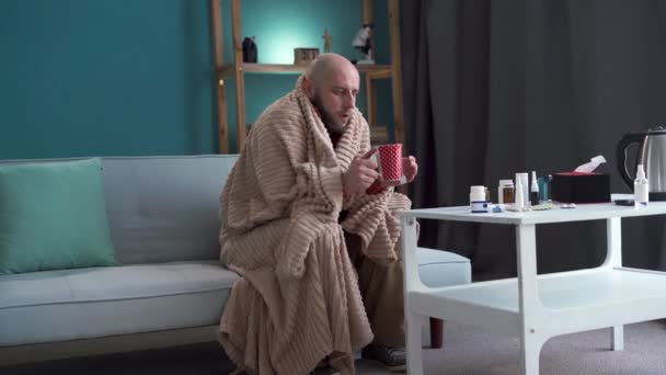 Millennial zieke man zit op de bank thee te drinken die lijdt aan griep. Kopieerruimte - Video