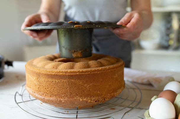 Enlever ou enlever le moule à pâtisserie d'un gâteau bundt frais cuit au four par les mains des femmes - Photo, image