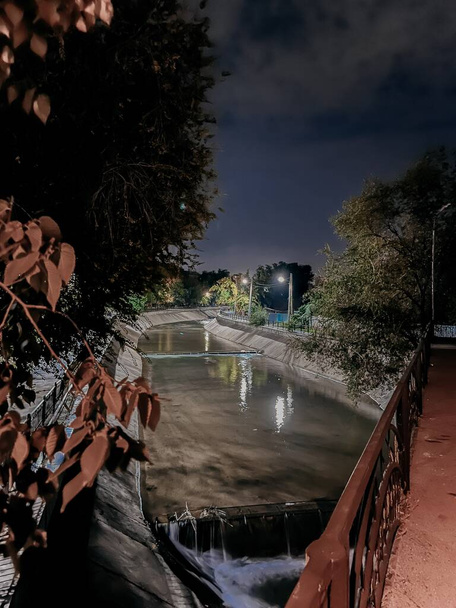 Foto a lunga esposizione di un fiume cittadino di notte, con acqua riflettente liscia e luci della città brillanti. - Foto, immagini