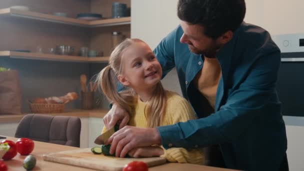 自宅で幸せな家族 医療保険の配達 健康的な栄養ヘルスケア 父親は子供の娘を教えるのに役立ちます 新鮮なキュウリ野菜キッチンは一緒に調理サラダを準備します - 映像、動画