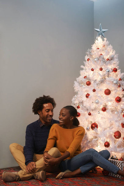 Paar, Kerstmis en boom in appartement voor vakantie viering voor het winterseizoen, decoratie of hechting. Man, vrouw en gelukkig thuis voor nu geven in Amerika voor evenement, verbinding of samen. - Foto, afbeelding