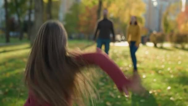 Happy Caucasian family in park parents with little child kid play game outdoors autumn daughter girl run dad running to daddy raise lift up in air spin funny playing having fun together love holiday - Footage, Video