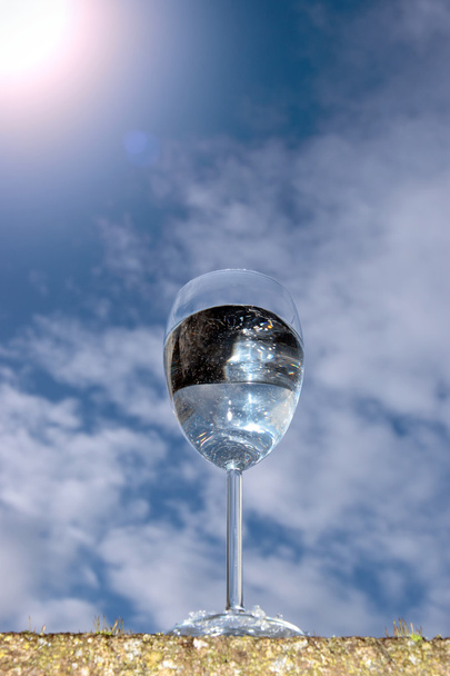szklankę wody przed rażące słoneczne niebo - Zdjęcie, obraz