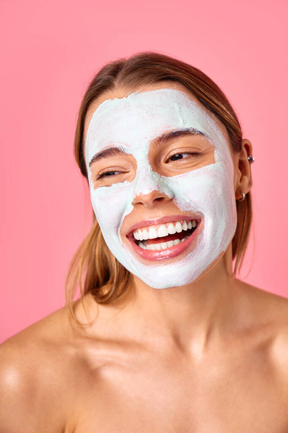 Bella donna felice utilizzando maschera viso argilla detergente per punti neri e pori allargati isolati su sfondo rosa. Cura della pelle, cosmetologia, concetto di bellezza. - Foto, immagini