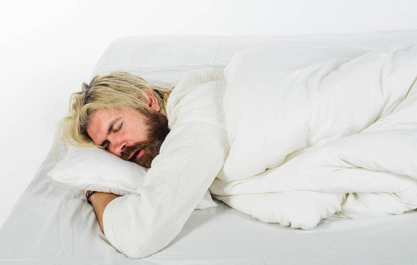 -Καληνύχτα. Όμορφος γενειοφόρος άντρας κοιμάται σε άνετο μαξιλάρι στο κρεβάτι στο σπίτι. Νυσταγμένος άντρας με πιτζάμες κοιμάται στο κρεβάτι στην κρεβατοκάμαρα. Αναψυχή, βαθύς ανδρικός ύπνος, χρόνος ανάπαυσης και έννοια του υγιούς ύπνου - Φωτογραφία, εικόνα