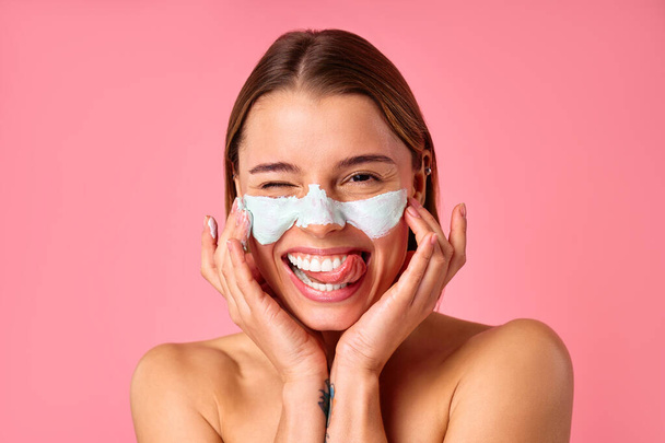 Belle femme heureuse utilisant un masque facial nettoyant pour les points noirs et les pores dilatés isolés sur fond rose. Soins de la peau, cosmétologie, concept beauté. - Photo, image