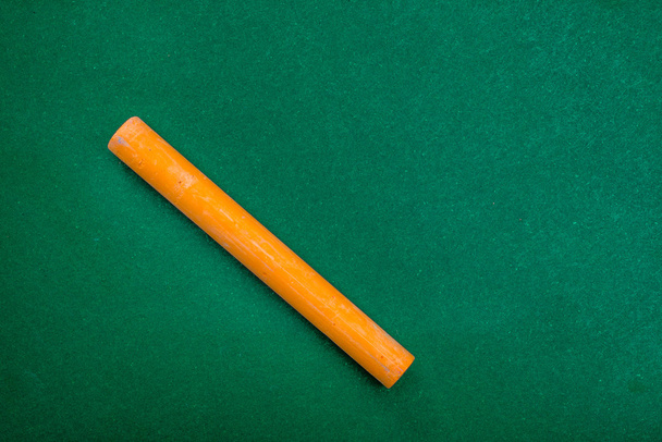 Single orange piece of chalk on green - Photo, Image