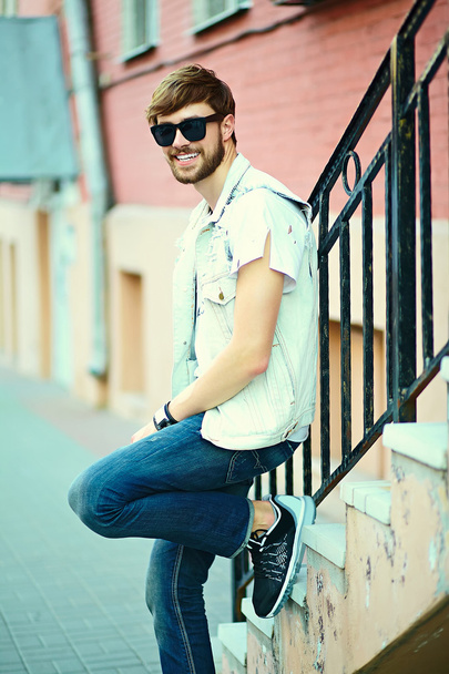 Funny smiling hipster handsome man guy in stylish cloth in the street in sunglasses - Foto, imagen