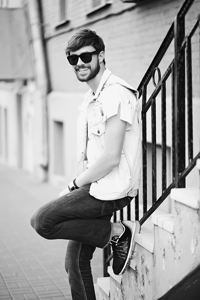 Funny smiling hipster handsome man guy in stylish cloth in the street in sunglasses - Фото, зображення