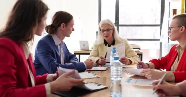 Mature lady manager performs information to coworkers at meeting in company premise. Serious woman executive explains new ideas to employees slow motion - Footage, Video