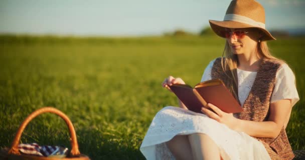 Cattura l'essenza del tempo libero come una donna sorridente indulge in relax su un'accogliente coperta da picnic in mezzo alla natura bellezza - Filmati, video