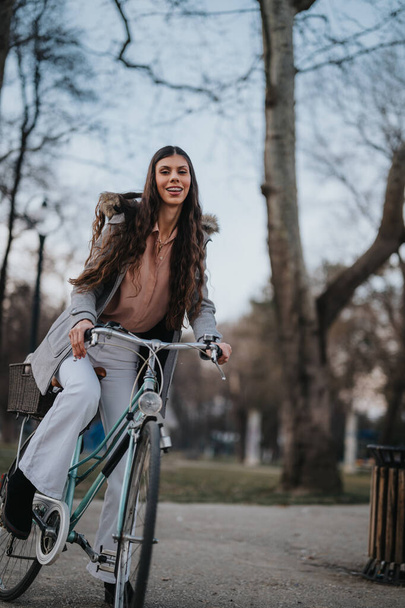 Een lachende zakenvrouw met een fiets maakt een ontspannen ritje in een stadspark, ademt geluk en evenwicht tussen werk en privéleven uit. - Foto, afbeelding