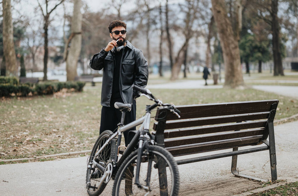Ein Unternehmer genießt mit seinem Fahrrad einen entspannten Moment in einer ruhigen Parklandschaft. - Foto, Bild
