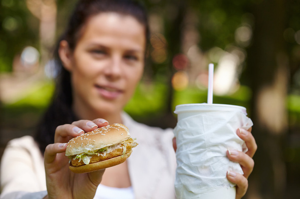 Γυναίκα τρώει χάμπουργκερ και κοκτέιλ - Φωτογραφία, εικόνα