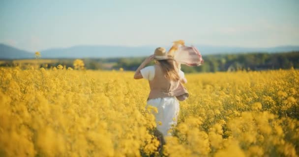Un ritratto accattivante di una donna che passeggia con grazia in mezzo a un vibrante campo di stupri, evocando sensazioni di serenità e connessione con la natura - Filmati, video