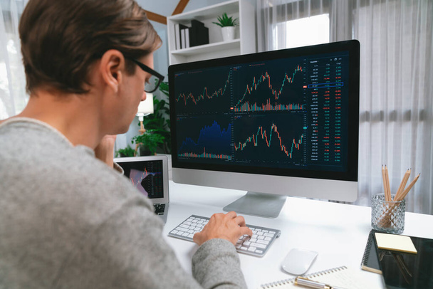 Business trader using computer and laptop to search highest profit value of dynamic increased stock market graph on working desk, analyzing exchange rate value on screen at modern office. Pecuniary. - Photo, Image
