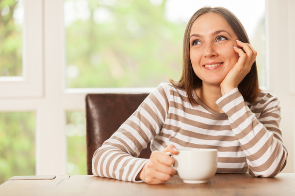 усміхнена брюнетка жінка має чашку кави
 - Фото, зображення