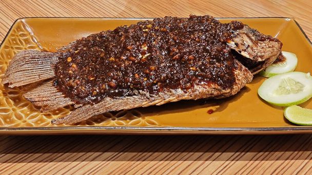 Savory Grilled Gurame Fish with Candlenut Spice on Elegant Golden Plate. - Photo, Image