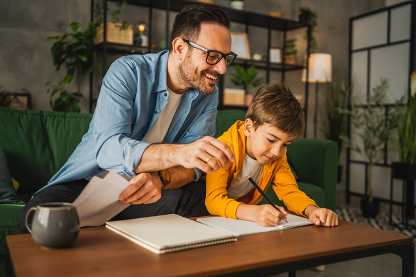 Apa szemüveggel és fiával házi feladatot csinál, és otthon együtt tanulnak. - Fotó, kép