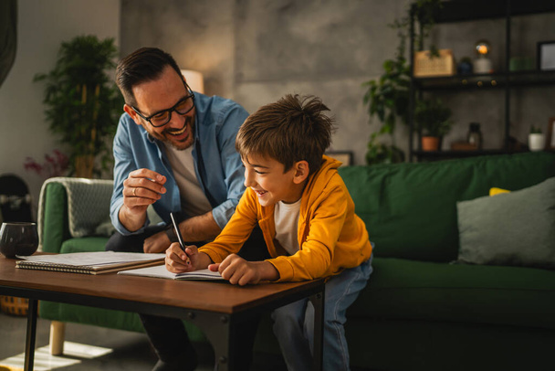 Father with eyeglasses and son do homework and learn together at home - Photo, Image