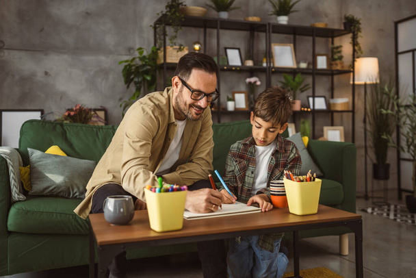 Father with eyeglasses and son caucasian draw and paint together at home leisure activity - Photo, image