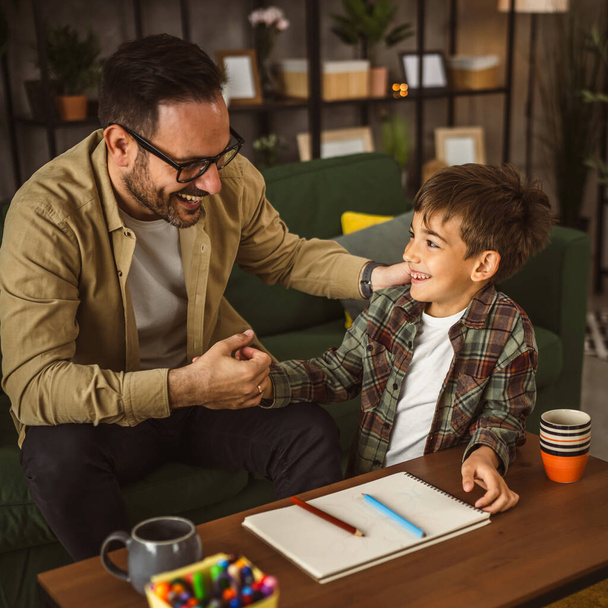 Padre con anteojos e hijo caucásico dibujar y pintar juntos en casa actividad de ocio - Foto, Imagen