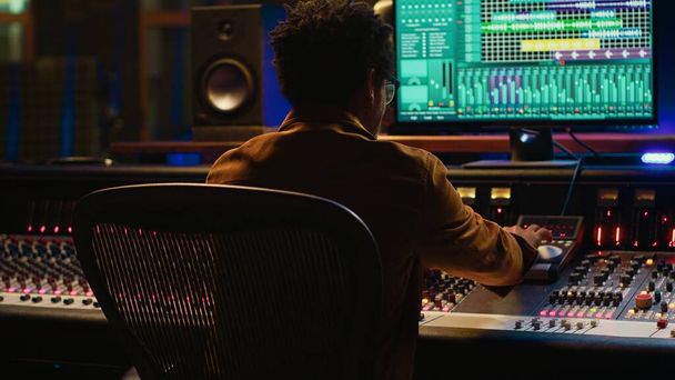 Sounddesigner entspannt sich nach dem Mischen und Mastering von Tracks auf einem Studiostuhl und beendet sein Musikprojekt im Kontrollraum. Afroamerikanischer Audio-Experte produziert neue Songs. Kamera A. - Foto, Bild
