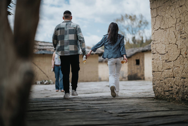Una pareja cogida de la mano mientras caminaba por un antiguo pueblo rústico en un viaje, encarnando aventura y compañía. - Foto, imagen