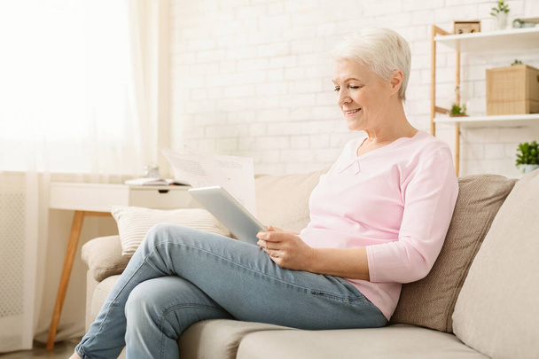Prends de la paperasse. Femme âgée travaillant avec des documents et une tablette numérique à la maison, espace libre
 - Photo, image