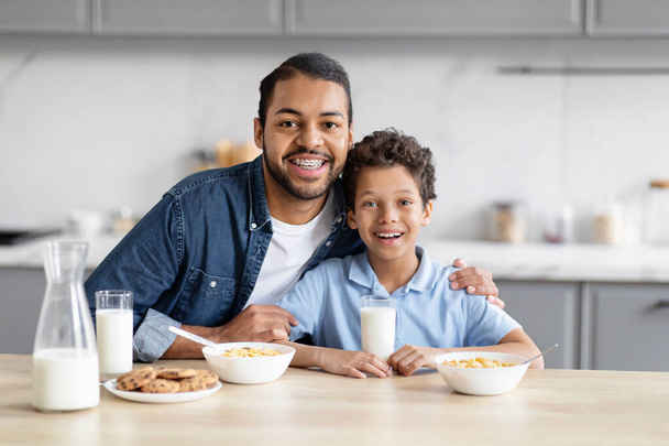 De intieme band tussen een Afro-Amerikaanse vader en zoon terwijl ze samen ontbijten in een keuken roept de geest van familiebanden op. - Foto, afbeelding