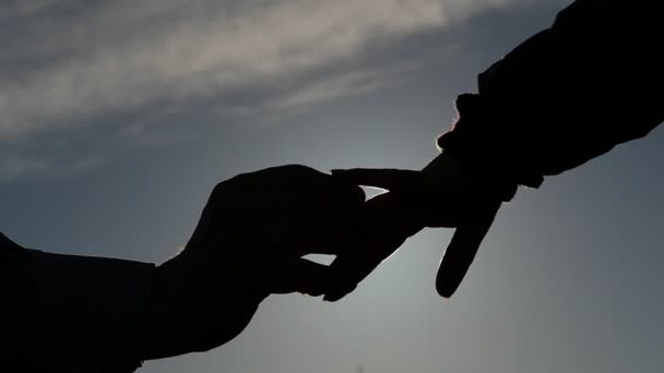 Silueta de la mano del hombre poniendo un anillo en el dedo de la mujer cámara lenta con sol parpadeando
 - Metraje, vídeo
