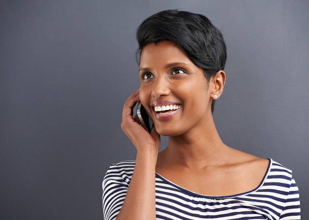 Gelukkige vrouw, communicatie en gesprek met telefoon voor oproep op een grijze studio achtergrond. Jonge vrouwelijke persoon met glimlach en praten op mobiele smartphone voor vriendelijke discussie over mockup ruimte. - Foto, afbeelding