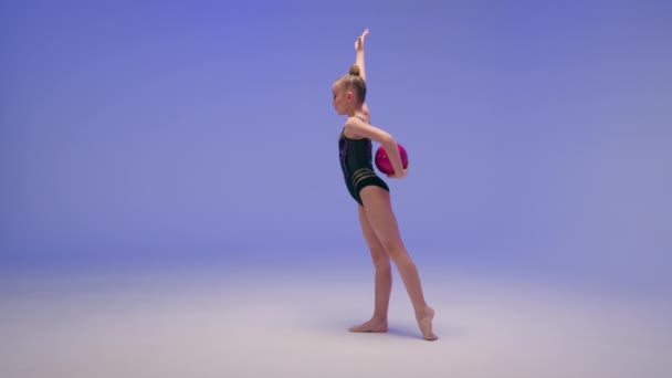 Caucasian little girl flexible acrobat gymnast sport dancer female young ballerina child kid schoolgirl athlete in blue studio stretching perform bend body pose with gymnastic ball gymnastics exercise - Footage, Video