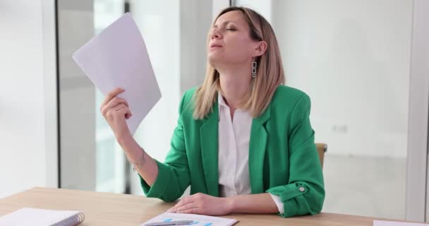 Bizneswoman czuje się przegrzana i używa wentylatora dokumentów. Ciepło w miejscu pracy i kontrola klimatu w biurze - Materiał filmowy, wideo
