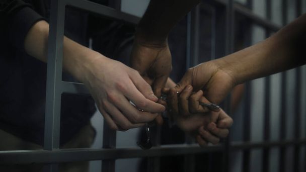 Ув'язнений знімає наручники з молодого в'язня. Багато етнічних підлітків відбувають покарання у вигляді позбавлення волі у виправному закладі або СІЗО. Молоді в'язні у тюремній камері. Система правосуддя. крупним планом. - Фото, зображення