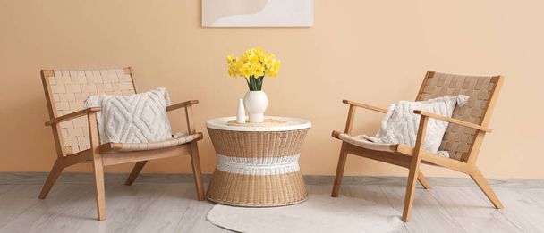 Interieur des Wohnzimmers mit Sesseln, Narzissenblumen und Couchtisch - Foto, Bild