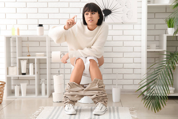 Mladá žena s tampónem sedí na záchodové míse doma - Fotografie, Obrázek