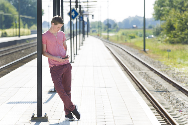 Man Using Mobile Phone While Waiting On Railway Platform - Photo, Image