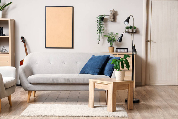 Interiér světlého obývacího pokoje s šedou pohovkou, stolem a rostlinami - Fotografie, Obrázek