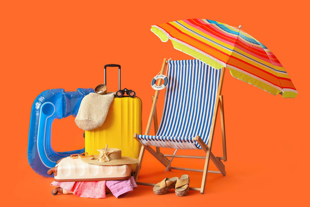 Валізи з пляжними аксесуарами, біноклями та стільцем на кольоровому фоні - Фото, зображення