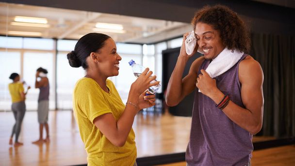 People, drinking water and break in dance studio, smile and relax from practice or learning routine. Partners, happy and laugh for humor in training, hydration and nutrition for exercise or workout. - Photo, Image