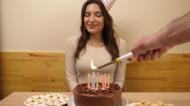Дівчина сидить перед столом зі святковим тортом, в якому запалюються свічки. Концепція святкування дня народження. - Кадри, відео