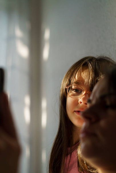 Портрет дівчини-підлітка в окулярах і мама з смартфоном в руці - Фото, зображення