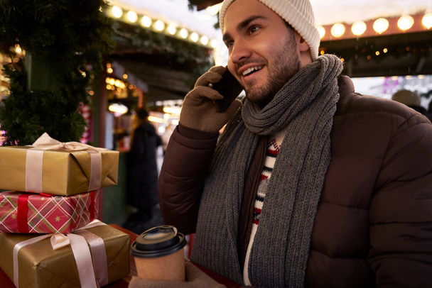 Man belt via telefoon op de kerstmarkt - Foto, afbeelding