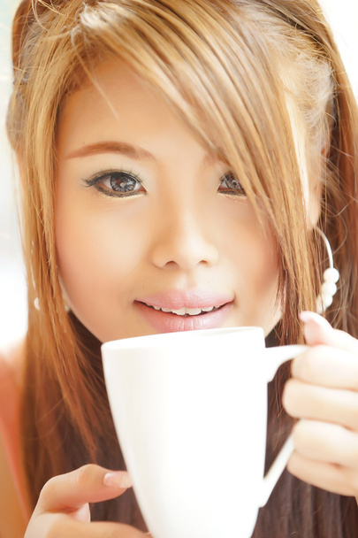 Closeup beautiful woman sitting in cafe holding and drinking cof - Photo, Image
