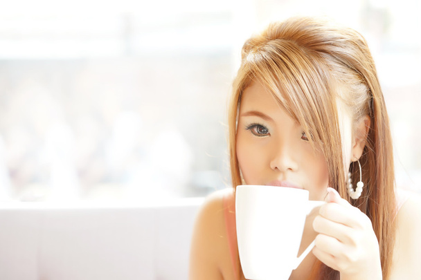 Primer plano hermosa mujer sentada en la cafetería sosteniendo y bebiendo cof
 - Foto, Imagen